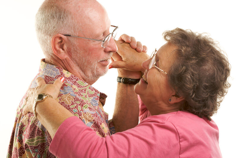 Older couple dancing at home with a white background in Dallas, TX