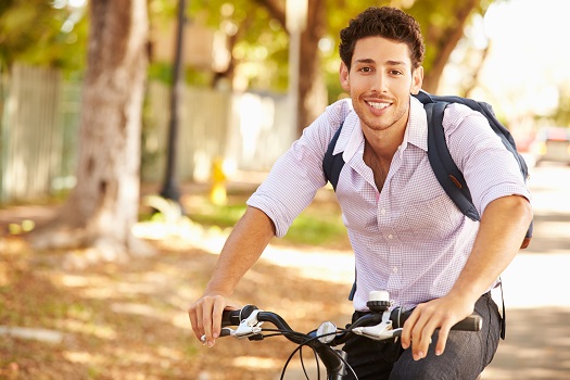 Young Man Cycling Along Street To Work